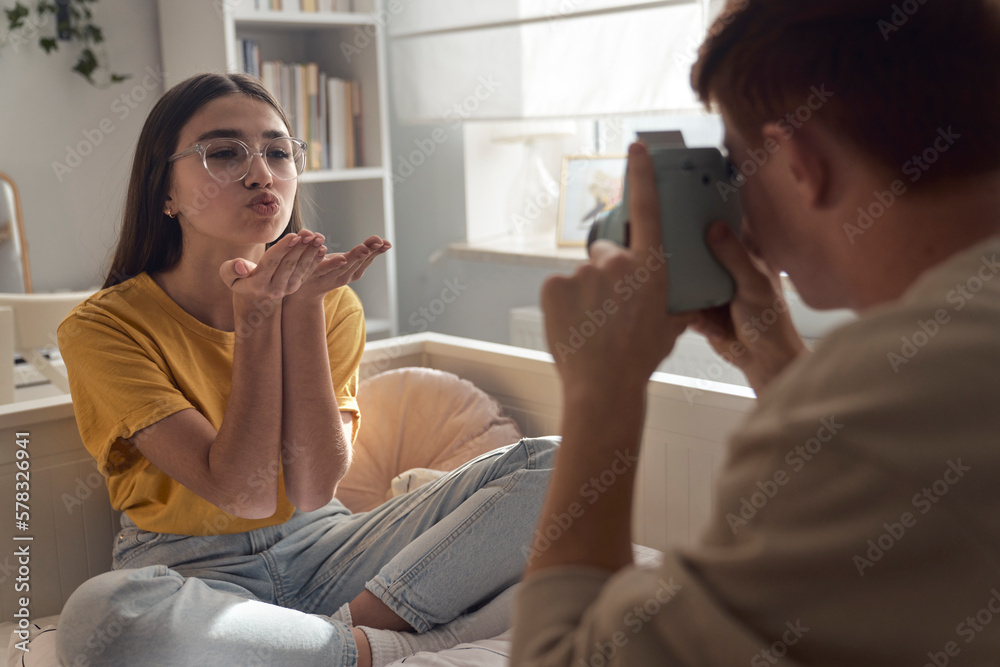 Two caucasian teenage friends taking photos in the bedroom