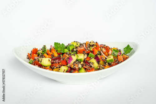 Black quinoa salad with red peppers, cherry tomatoes, red beans, red onion and cucumbers, in a white ceramic plate. Vegan food, healthy eating