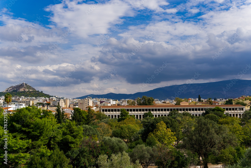 The Stoa of Attalos surrounded by hills covered in greenery under the cloudy sky in Greece