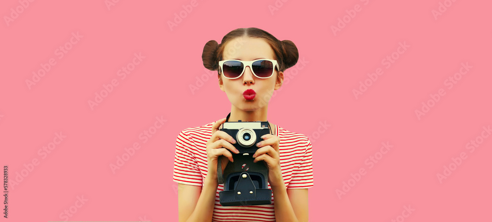 Portrait of happy young woman photographer with film camera, female with cool girly hairstyle on pink background Portrait of happy young woman photographer with film camera, female with cool girly hairstyle on pink background