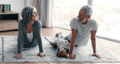 Fotografiet Cheerful senior couple practicing yoga with their dog at home together