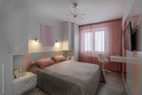 A modern bedroom in blue  pink and white colors with muffled lighting. Real photo
