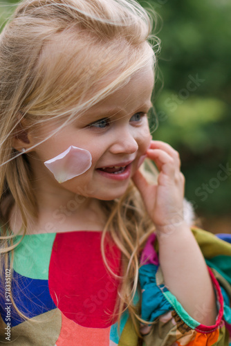 Portrait of little toddler girl in blossoming rose garden. Cute beautiful lovely child having fun with roses and flowers in a park on summer sunny day. Happy smiling baby. photo