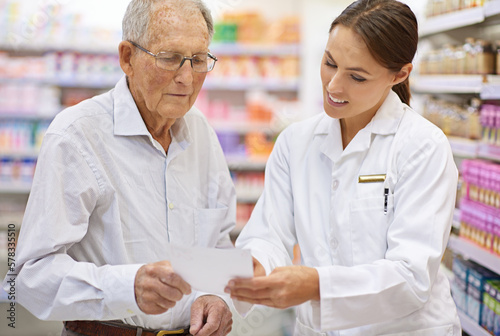 Ensuring her client is well informed. a young pharmacist helping an elderly customer with his prescription. photo