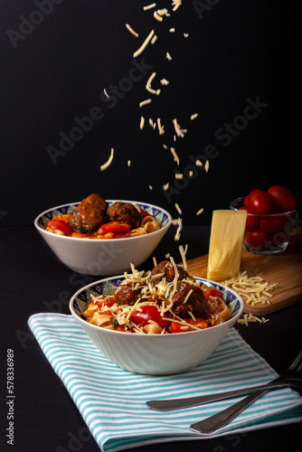 Classic italian tagliatelle spaghetti pasta with tomato sauce, meatballs, parmesan cheese and basil in plate on dark table. Dark food, dark mood