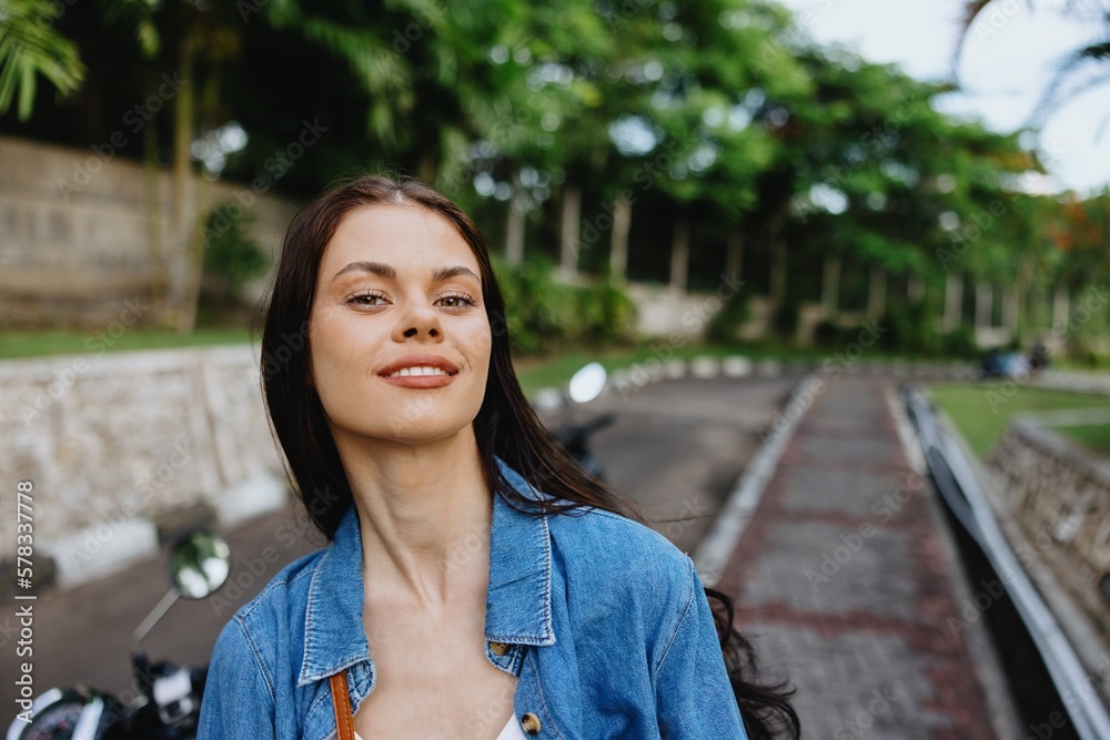 Portrait of a woman brunette smile with teeth walking outside against a backdrop of palm trees in the tropics, summer vacations and outdoor recreation, the carefree lifestyle of a freelance student. Portrait of a woman brunette smile with teeth walking outside against a backdrop of palm trees in the tropics, summer vacations and outdoor recreation, the carefree lifestyle of a freelance student.