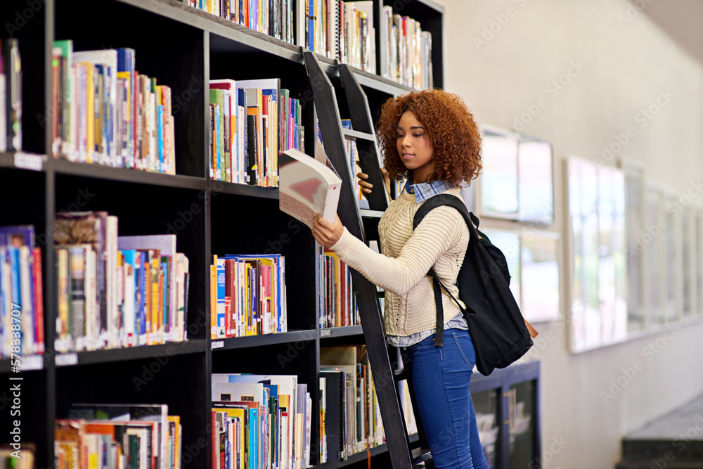 She found what she was looking for. a young woman studying from a book while standing by a library bookshelf. She found what she was looking for. a young woman studying from a book while standing by a library bookshelf.