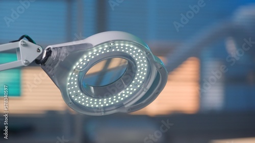 Round magnifier lamp with spot LEDs. White glowing lamp on a blurred blue background close up. Equipment for lighting and magnifying objects in a beauty salon or laboratory.