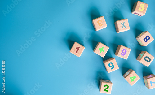 Fototapeta Naklejka Na Ścianę i Meble -  Colorful wooden cubes with numbers scattered on blue background. learning, increasing IQ, development for children. Top view of children's toys. Educational games.
