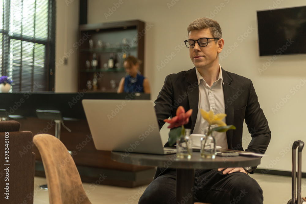 A male traveler enjoys using airline business lounge at a terminal waiting for departure. Business man uses computer laptop to check his travel plan and boarding in a lobby room. A male traveler enjoys using airline business lounge at a terminal waiting for departure. Business man uses computer laptop to check his travel plan and boarding in a lobby room.