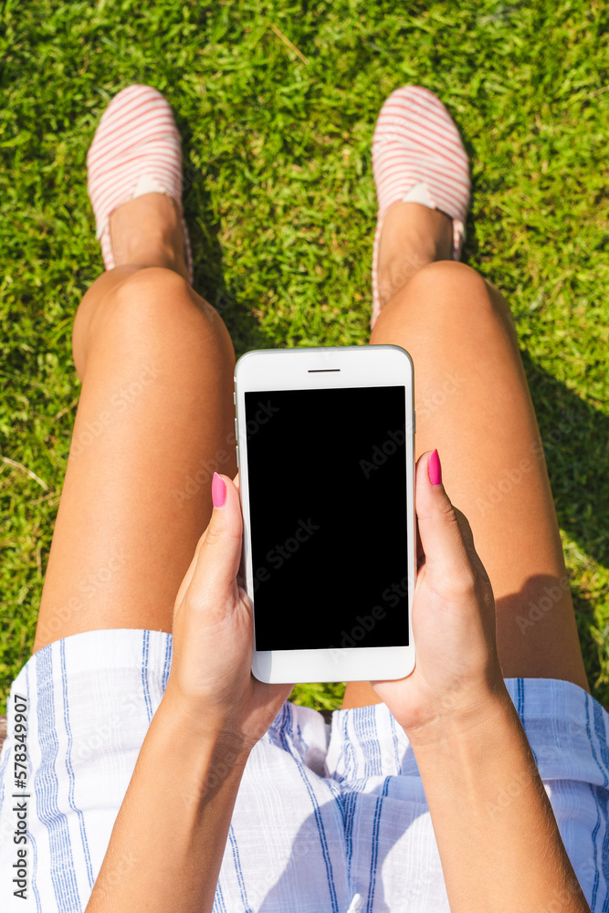 Young woman in summer outfit using smart phone with empty screen