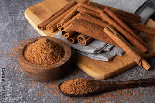 Fototapeta Naklejka Na Ścianę i Meble -  Cinnamon sticks on a wooden background. Cinnamon spice in a spoon and bowl. Ceylon cinnamon. Cinnamon powder.