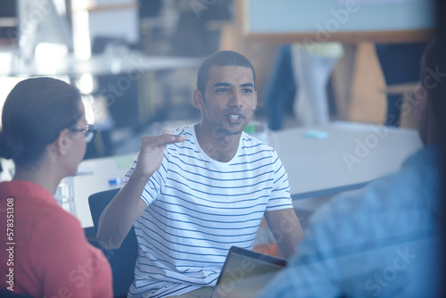 Free Download Sharing ideas with the team. Through the glass shot of a group of designers discussing ideas in a meeting. - GFXLoad