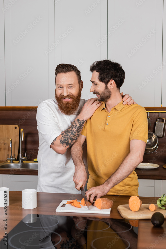 Cheerful gay man hugging happy partner cooking at home. Cheerful gay man hugging happy partner cooking at home.