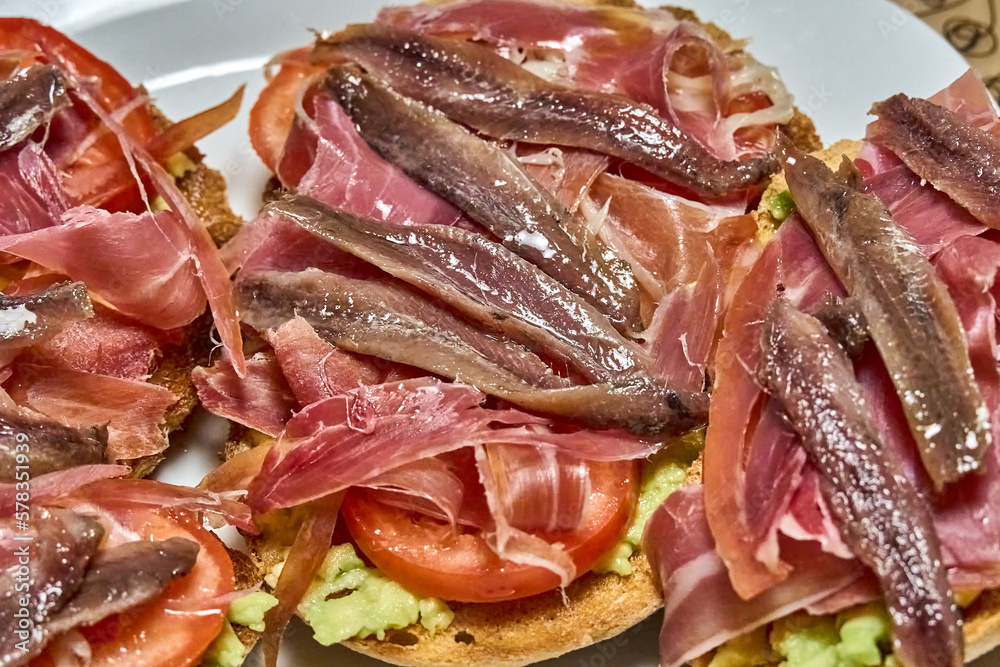 Suggestive Iberian ham toasts, tomato slices and fresh avocado.