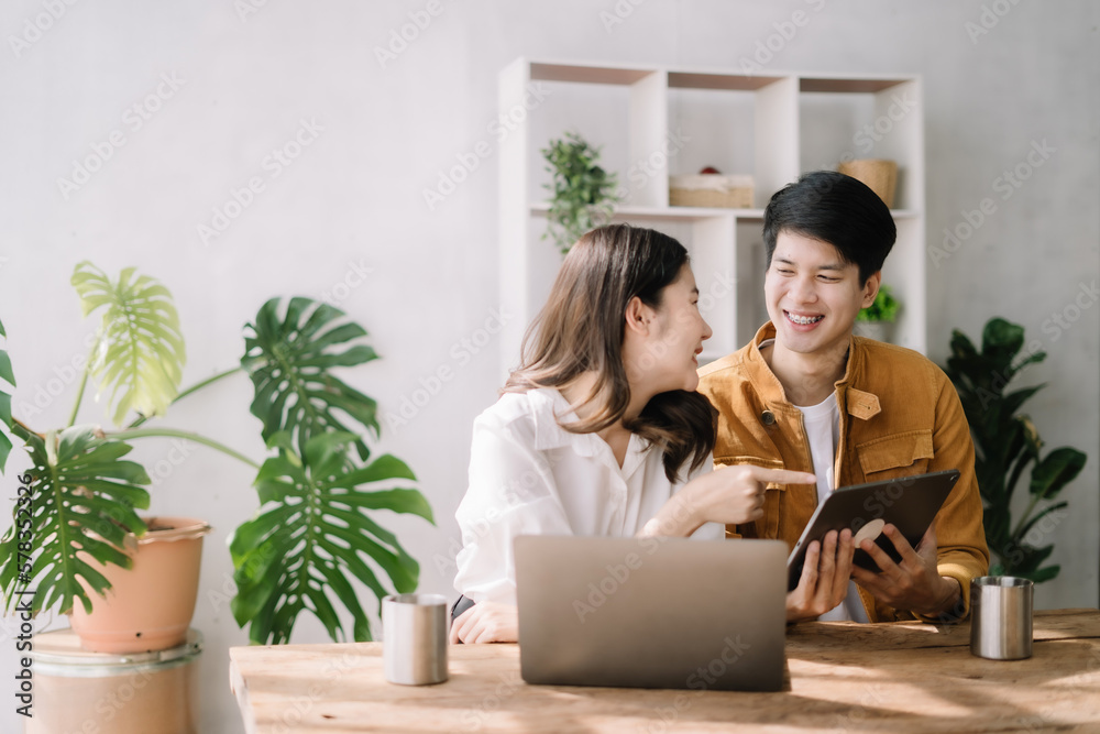 Happy asian young couple smile and looking to screen tablet with laptop at home the morning. Happy asian young couple smile and looking to screen tablet with laptop at home the morning.