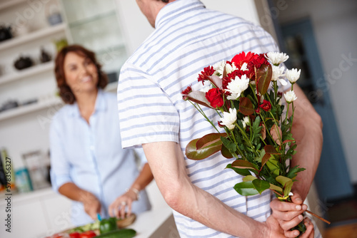 Keeping their love fresh. a husband surprising his wife with a bunch of flowers at home.
