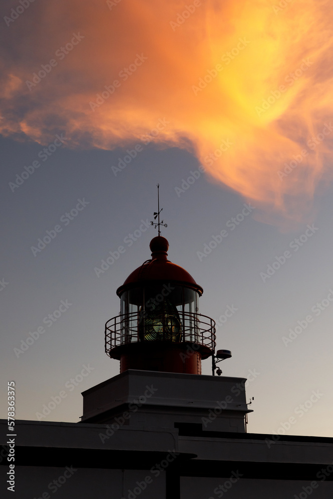 Ocean lighthouse during the sunset. Dramatic clouds on the background.