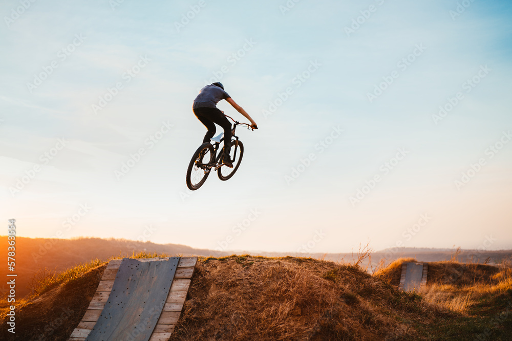 Obraz premium Young man on a mountain bike performing a dirt jump