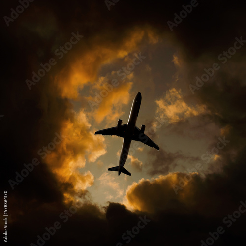 Airplane flies through orange dramatic clouds