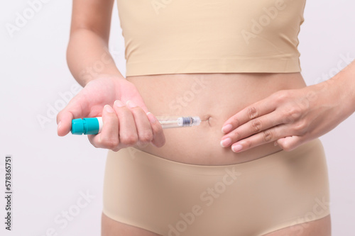 Close up woman using IVF treatment injection on belly to prepare reproductive fertility , Ovulation stimulation ..