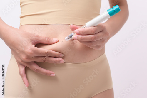 Close up woman using IVF treatment injection on belly to prepare reproductive fertility   Ovulation stimulation ..