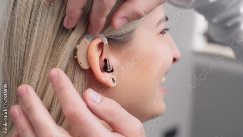 Front view close up of a female patient being fitted with a hearing aid by a doctor photo