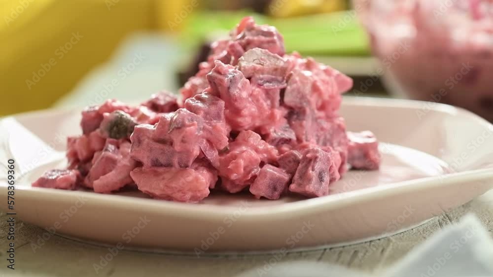 The cook serves beet and potato salad on the plate.
The cook serves beet and potato salad on the plate.
