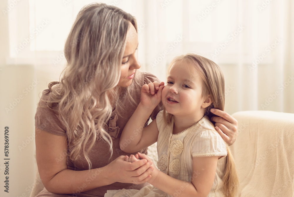 Smiling preschool girl sitting on mommies lap at home. Carefree mom and little girl laughing while playing at home. Love, warm family relationships. Happy kid with mum spending free time together Smiling preschool girl sitting on mommies lap at home. Carefree mom and little girl laughing while playing at home. Love, warm family relationships. Happy kid with mum spending free time together