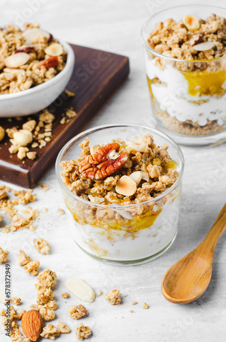 Granola and Yogurt Parfaits, Healthy Breakfast or Snack, Muesli with Nut Mix and Honey on Bright Concrete Background