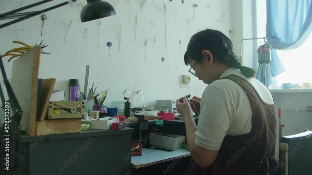 The girl works in her atmospheric craft workshop with jewellery. The girl works in her atmospheric craft workshop with jewellery.