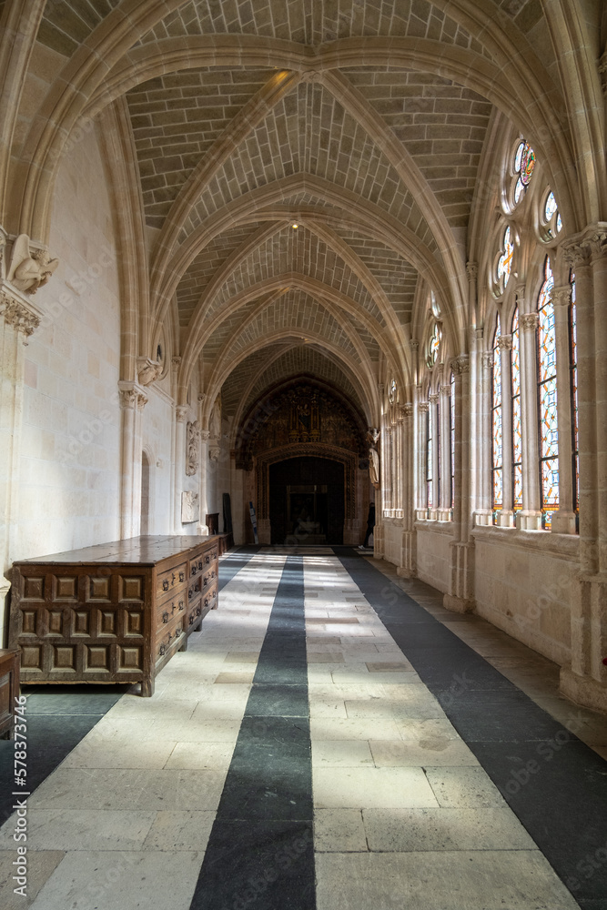 Pasillo lleno de vidrieras a un lado y de aristas en el techo de la Catedral de Burgos por donde pasean los turistas.