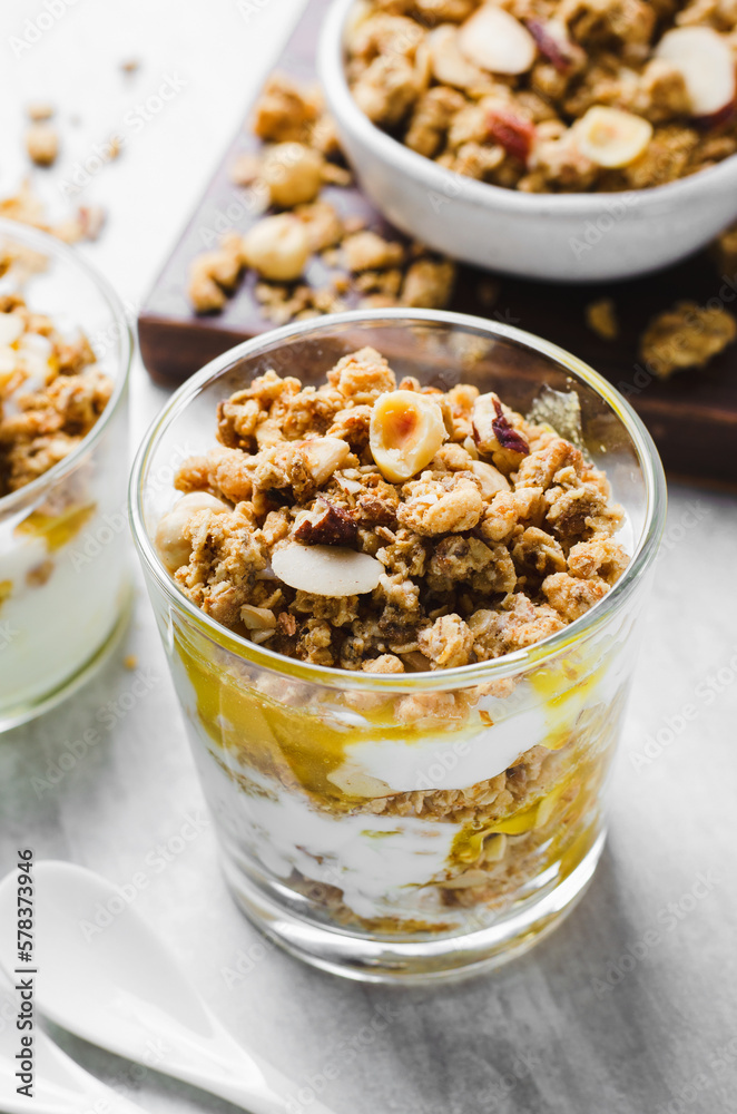 Granola and Yogurt Parfaits, Healthy Breakfast or Snack, Muesli with Nut Mix and Honey on Bright Concrete Background Granola and Yogurt Parfaits, Healthy Breakfast or Snack, Muesli with Nut Mix and Honey on Bright Concrete Background