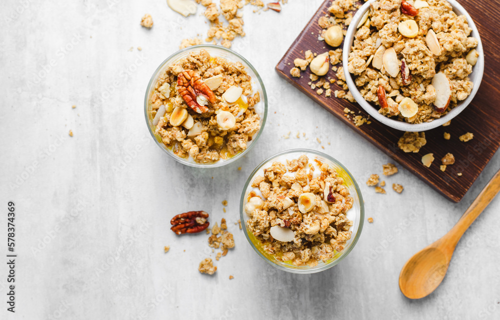 Granola and Yogurt Parfaits, Healthy Breakfast or Snack, Muesli with Nut Mix and Honey on Bright Concrete Background Granola and Yogurt Parfaits, Healthy Breakfast or Snack, Muesli with Nut Mix and Honey on Bright Concrete Background