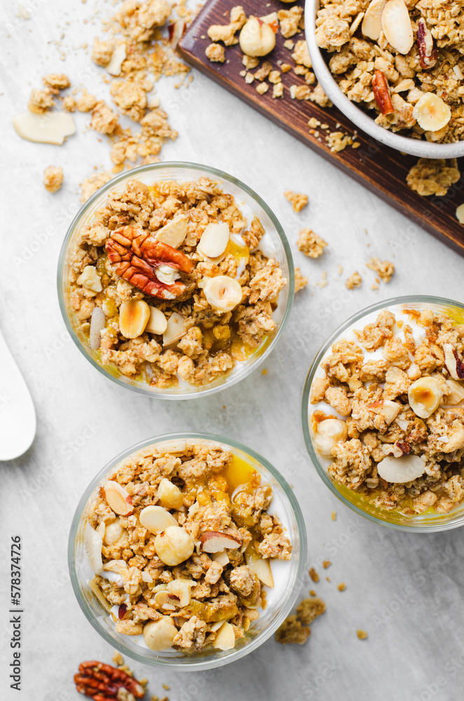 Granola and Yogurt Parfaits, Healthy Breakfast or Snack, Muesli with Nut Mix and Honey on Bright Concrete Background Granola and Yogurt Parfaits, Healthy Breakfast or Snack, Muesli with Nut Mix and Honey on Bright Concrete Background