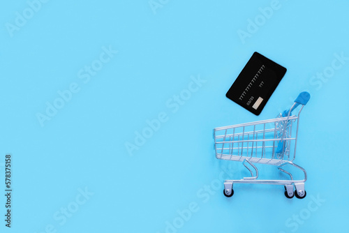 bank card and grocery cart on a blue background with space for text
