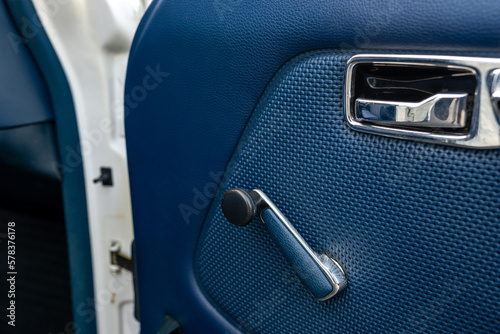Detail view of a car door with a window crank handle