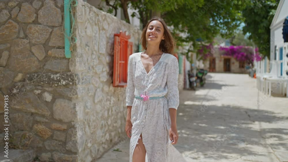 slow motion Smiling beautiful woman with flower wearing white dress walking street in old part of city enjoying vacation in Datcha, Turkey. slow motion Smiling beautiful woman with flower wearing white dress walking street in old part of city enjoying vacation in Datcha, Turkey.