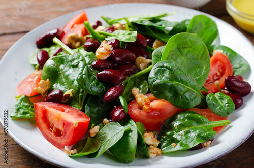 Red Bean Salad On Wooden Background, Fresh Salad with Spinach, Cherry Tomatoes, Walnuts, Beans and Mustard Dressing