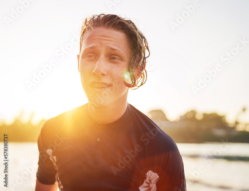 Obraz na płótnie Portrait of a handsome teen boy surfing rashguard on the sand Indian ocean beach with sunset on background