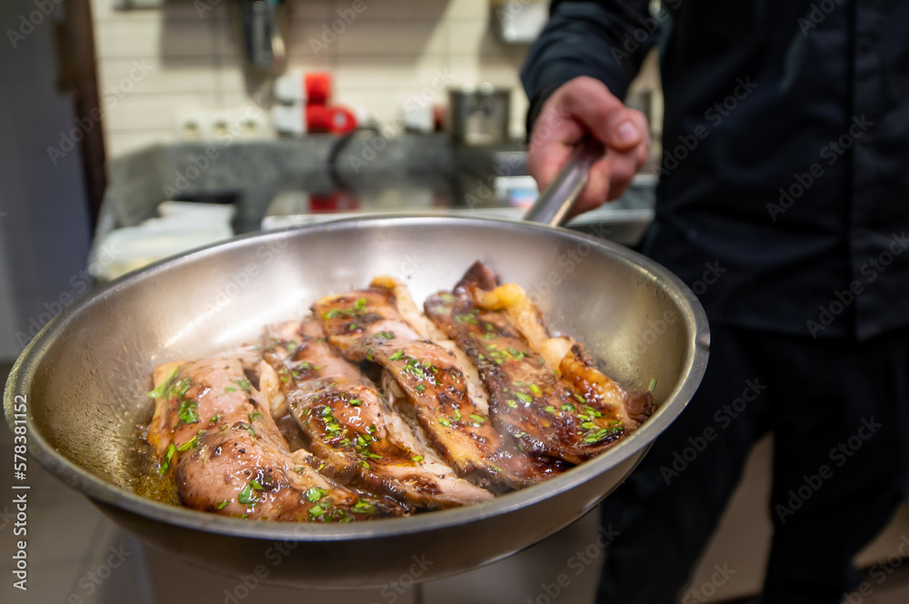 man chef cooking fried meat slice in frying pan on restaurant kitchen man chef cooking fried meat slice in frying pan on restaurant kitchen