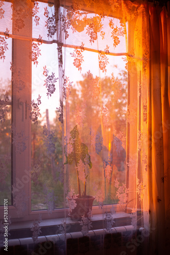 The sun's rays at sunset shine through the window, illuminating the house with a warm glow