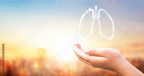 Hand holding white human lung shape on sunset PM2.5 city background