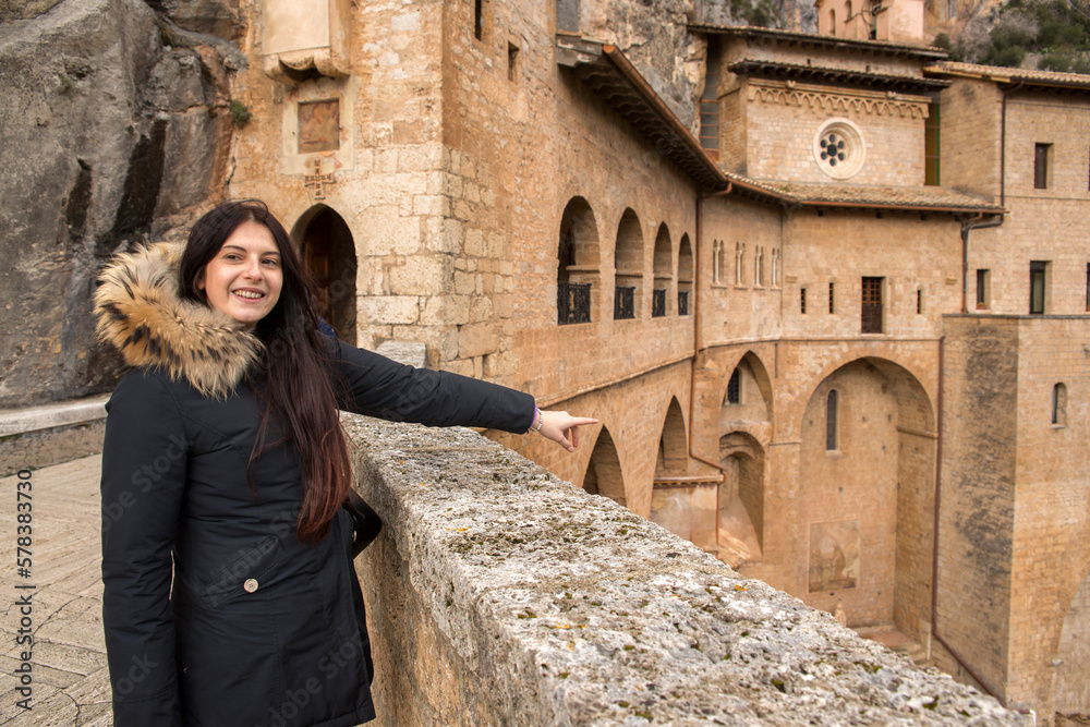 Girl at the Monastery of San Benedetto, or Sanctuary of the Sacro Speco. It's an ancient Benedictine monastery located in Subiaco, near Rome, Italy. Caucasian young woman with black hair on vacation.