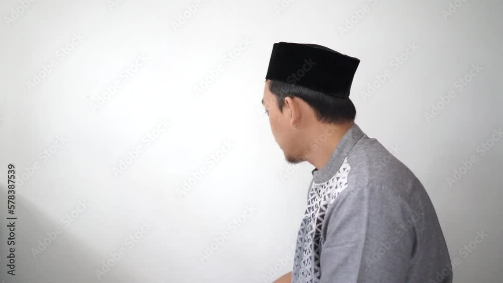 Indonesian Asian muslim man turned his head after salat prayer wears black hat peci or songkok