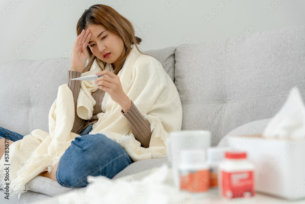 Young Asian woman having high fever while checking body temperature, female sneezing and runny nose with seasonal influenza, taking medicine, virus, coronavirus, illness, respiratory, allergic. Young Asian woman having high fever while checking body temperature, female sneezing and runny nose with seasonal influenza, taking medicine, virus, coronavirus, illness, respiratory, allergic.