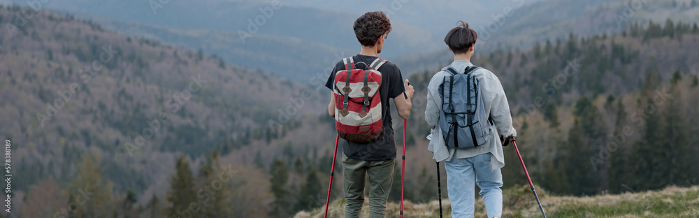 Back view on couple of travelers with walking sticks hiking high in mountains, Beauty of nature. Back view on couple of travelers with walking sticks hiking high in mountains, Beauty of nature.
