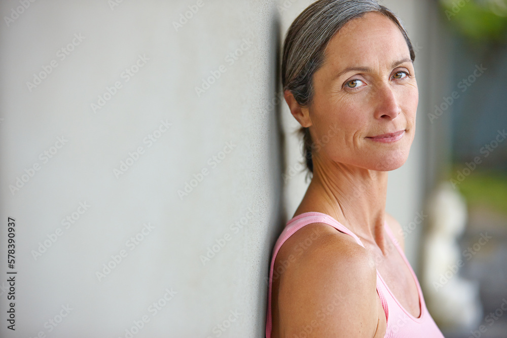 Its important to look after your body. Portrait of an attractive mature woman in gymwear leaning against a gray wall. Its important to look after your body. Portrait of an attractive mature woman in gymwear leaning against a gray wall.