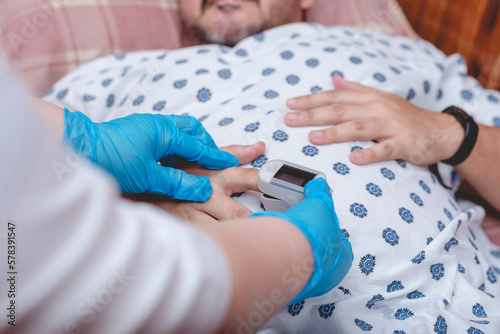 A nurse inserts an Oximeter on a patient's index finger. Checking blood oxygen or SpO2 levels. At the emergency ward of a hospital.