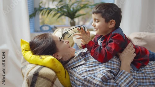 Cute boy play with mother glasses lying together. Realtime